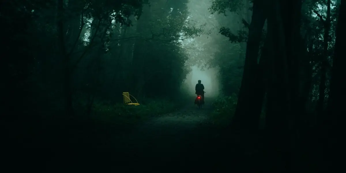 A lone cyclist in a misty green forest