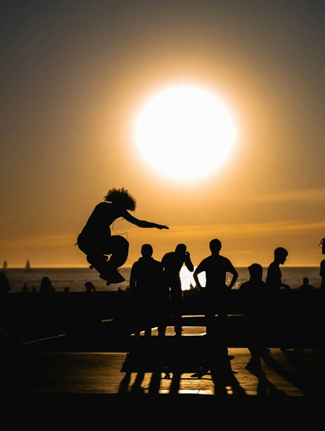 Friends silhouetted against a low sun, one of them mid-jump